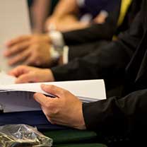 Hands at a meeting table holding notes.