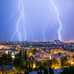 A town in the foreground and lightning striking in the distance