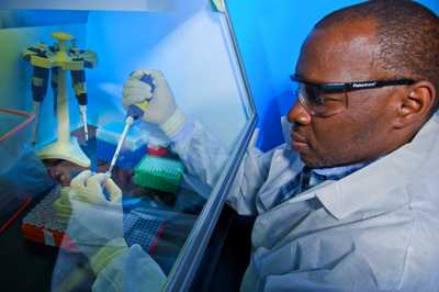 A researcher conducts a test behind a glass guard.