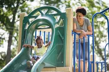 mother pushing child down slide