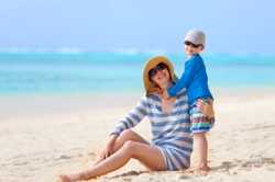 Foto de una madre y su hijo; ambos con gafas de sol, sombreros y camisas de mangas largas.