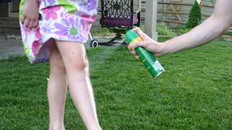 photo of a child, a dog, and an adult holding a bottle of insect repellant