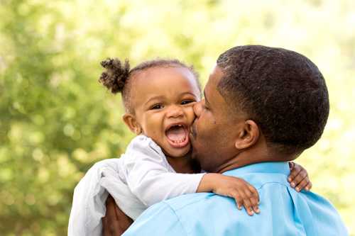 Dad holding smiling baby over his shoulder.