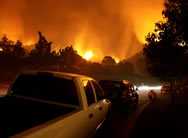 Cars along wildfire evacuation route. Wildfire in the background. 