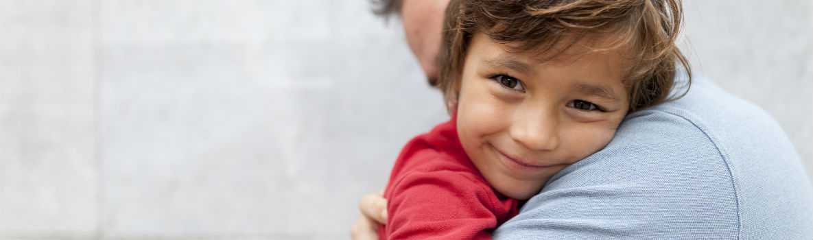 Photo of boy hugging his father around his neck