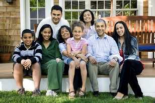 A large family seated on the steps of their home.