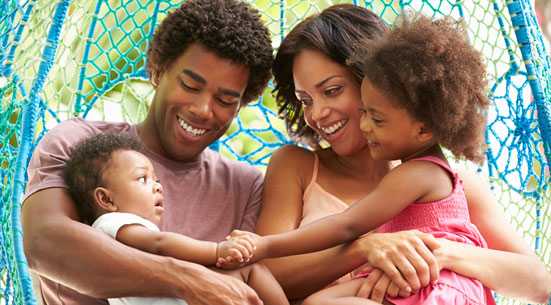 Family Relaxing On Outdoor Garden Swing Seat 