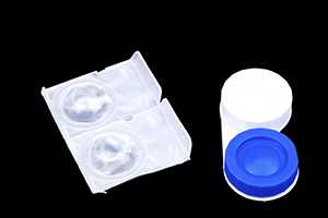 	soft contact lenses in a sealed plastic package on the left, and a hard contact lens case on the right