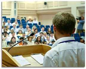 A boy of school age speaking at a podium in the school auditorium.