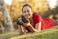 	A woman lying in the grass holding a camera