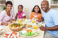 Imagen de una familia comiendo sentados alrededor de una mesa