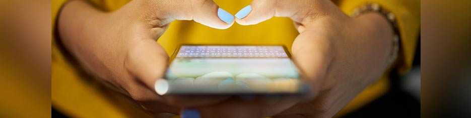 Young adult girl with blue nail polish  typing on her smartphone. 