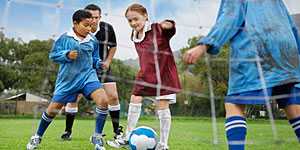 Photo of children playing soccer with a cloudy sky above