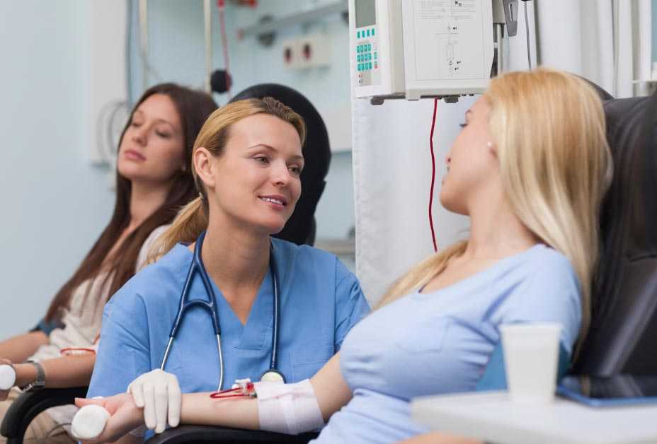 Nurse comforting woman giving blood