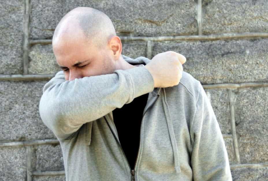 Man sneezing into sleeve