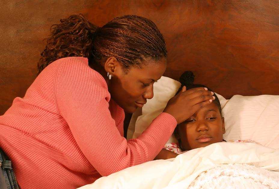 Mother checking daughter's forehead