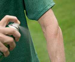 Man spraying insect repellant on arm