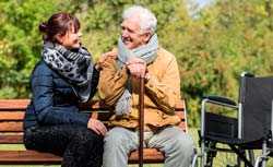 Adult daughter with senior father on park bench