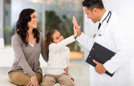 Mother with young daughter, who is high-fiving doctor