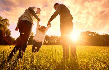 Mother and father lifting child off ground