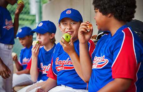 Boys' baseball team eating apples