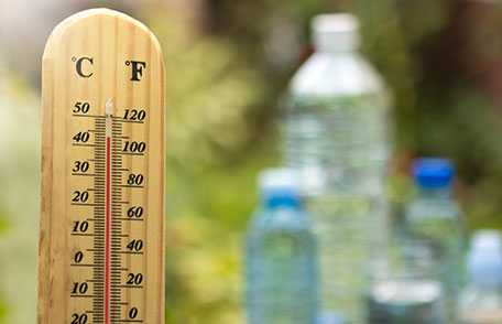 Hand holding thermometer with city skyline in background