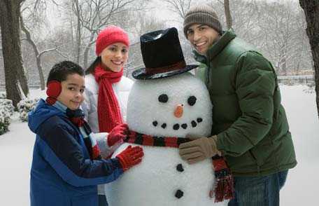 Hispanic family building snowman