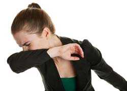 Woman sneezing into shirt sleeve