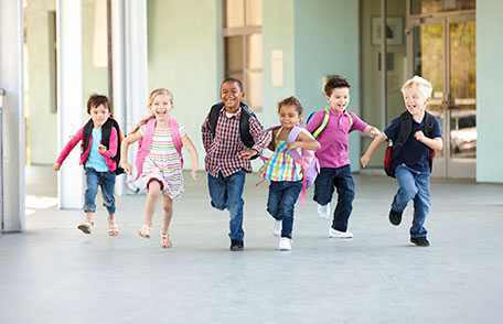 Group of children running down school hallway