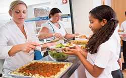 Lunch lady serving salad to student