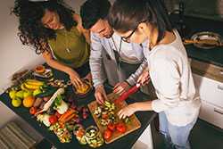 Young adults cutting fruits and vegetables