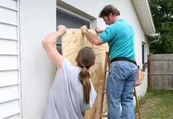 Two men nailing a board over a window