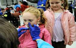 Little girl receiving nasal spray from school nurse