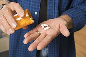 Man pouring pills in hand.