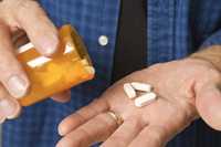 	Man pouring pills into his hand.