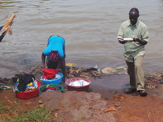 A fellow interacts with a woman at a water collection point. 