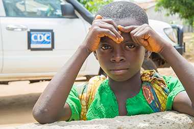 Boy in front of CDC surveillance truck during Ebola outbreak