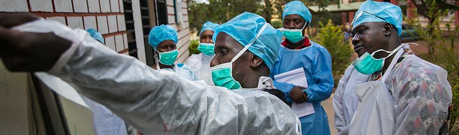 Public health workers wearing personal protective equipment review plans to contain an outbreak