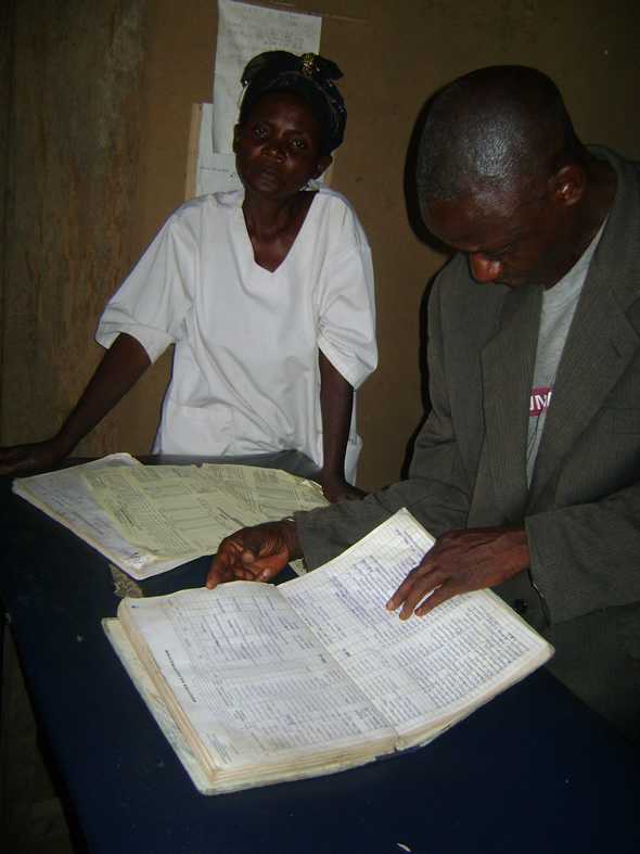 	DRC National Expert Group on Immunization Data Quality Member reviewing a child immunization register in Kasai Occidental. Photo courtesy of Daline Derival/CDC.