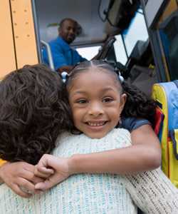 Photo: Girl hugging her Mom by the school bus