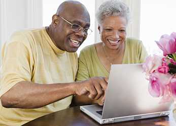 	Two older adults looking at a computer. 