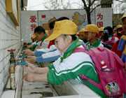 	Chinese school children washing their hands at an outdoor washing station.