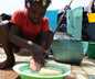 small child washing hands while squatting over a tub in a foreign country