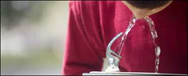 A boy drinking from a water fountain