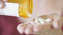 	woman pouring pills from a bottle into her hand