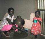 Mom and child in Kenya with clay pot for water storage.