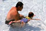 a father helping his daughter learn how to swim