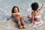 Two girls playing in the sand at the beach.