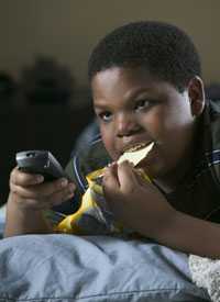 	fotografía de un niño mirando televisión y comiendo