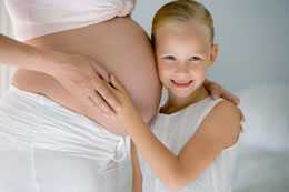 photo of a young girl hugging a pregnant woman